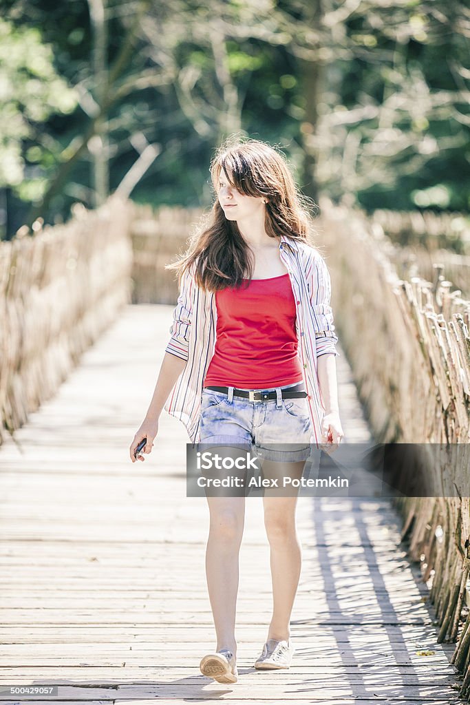 Teen girl walks next to country wicker fence 12-13 Years Stock Photo