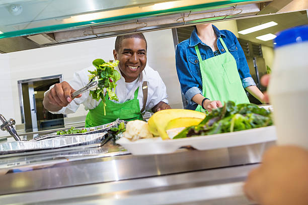 felice cuoco di mensa servire il pranzo insalata di studente in linea - porzione di cibo foto e immagini stock