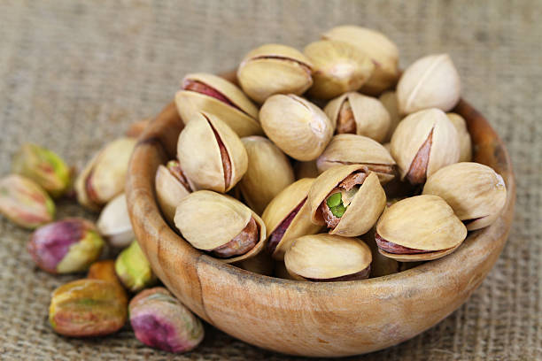 istock Pistachio nuts with and without shell in wooden bowl 500430175