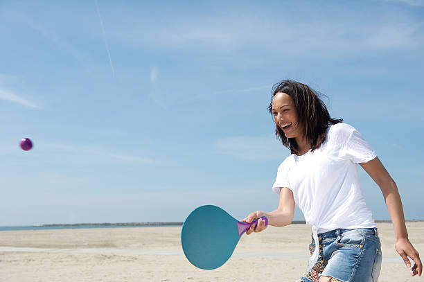 Woman playing paddle ball Portrait of a young woman playing paddle ball at the beach paddle ball stock pictures, royalty-free photos & images