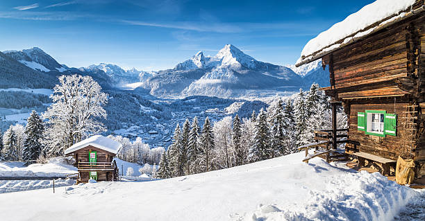 Winter wonderland with mountain chalets in the Alps Panoramic view of beautiful winter wonderland mountain scenery in the Alps with traditional mountain chalets on a cold sunny day with blue sky and clouds. bavarian alps photos stock pictures, royalty-free photos & images