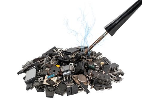 A Smoking soldering iron in a pile of old electronic components