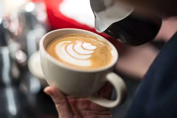 Photo of hand of barista making latte