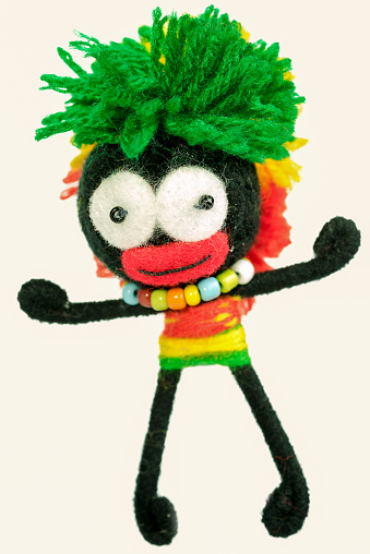 toy afro american boy in a traditional costume with bead and green hairs made from thread isolated on white background