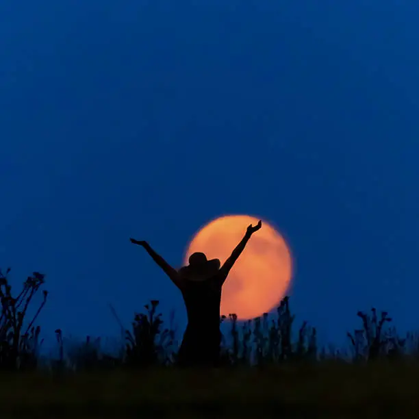 A woman with a hat from a full moon is happy