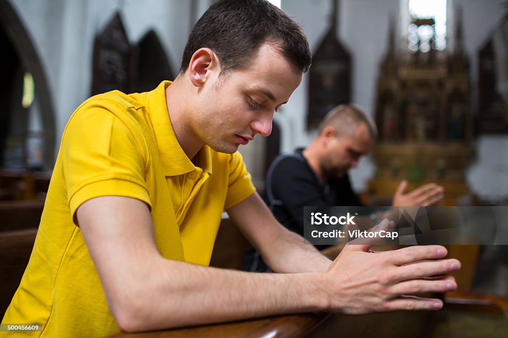 Handsome young man praying Handsome young man praying in a church Ancient Stock Photo