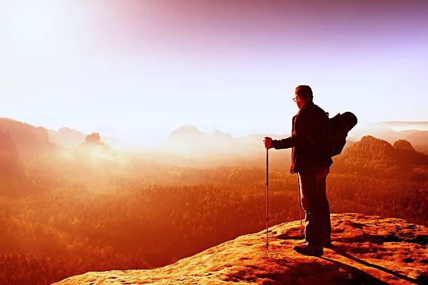 istock Backpacker with eyeglasses and poles in hand. Heavy orange mist 500457988