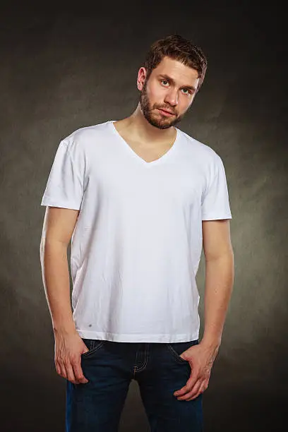 Portrait of handsome fashionable man in blank shirt. Young guy posing in studio on black. Casual fashion.