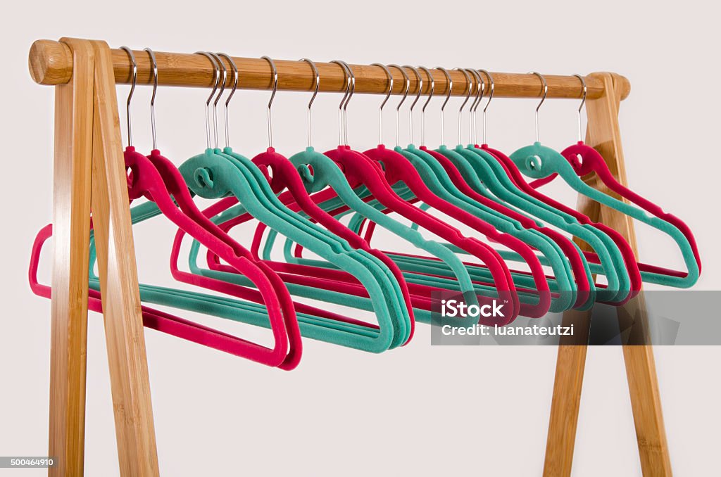 Rack of clothes with empty hangers. Close up on colorful pink and green felt hangers. Coathanger Stock Photo
