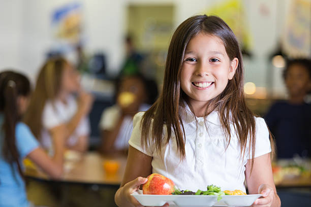 linda estudiante de escuela primaria hispana sostiene la bandeja de cafeteria alimentos - tray lunch education food fotografías e imágenes de stock