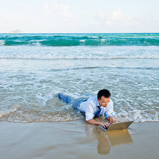 working at beach Young businessman on a beach with a laptop. soaked suit stock pictures, royalty-free photos & images
