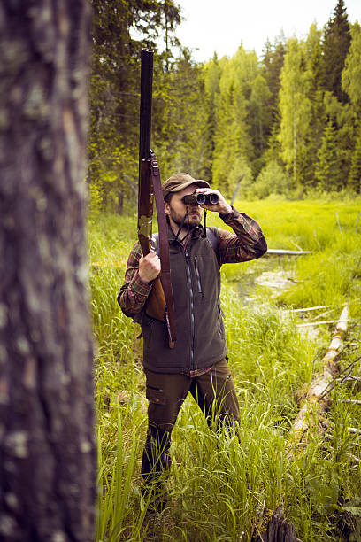 istock Hunter Looking Through Binoculars with a Shotgun in a Bog 500480120