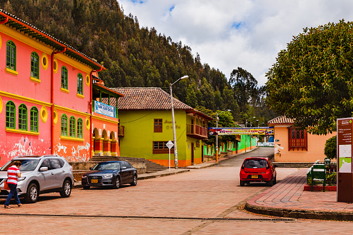 Nemocón, Colombia - September 19, 2015: One side of the main town square, in the town of Nemocón, in the department of Cundinamarca of the South America country of Colombia. Streetside establishments have their facades painted in the typical bright colours of Latin America; some cars are parked on the street.  Photo shot in the afternoon sunlight; horizontal format. Copy space.