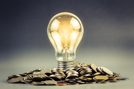 Light bulb and pile of coins
