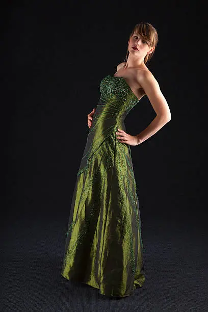 Slender and elegant young lady wearing a full length green ball gown.