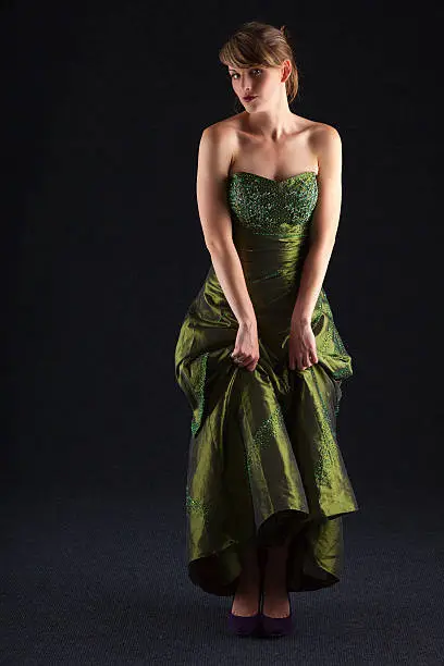 Slender and elegant young lady wearing a full length green ball gown.