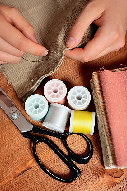 istock Close-up female hands sewing fabric on old wooden table 500493701