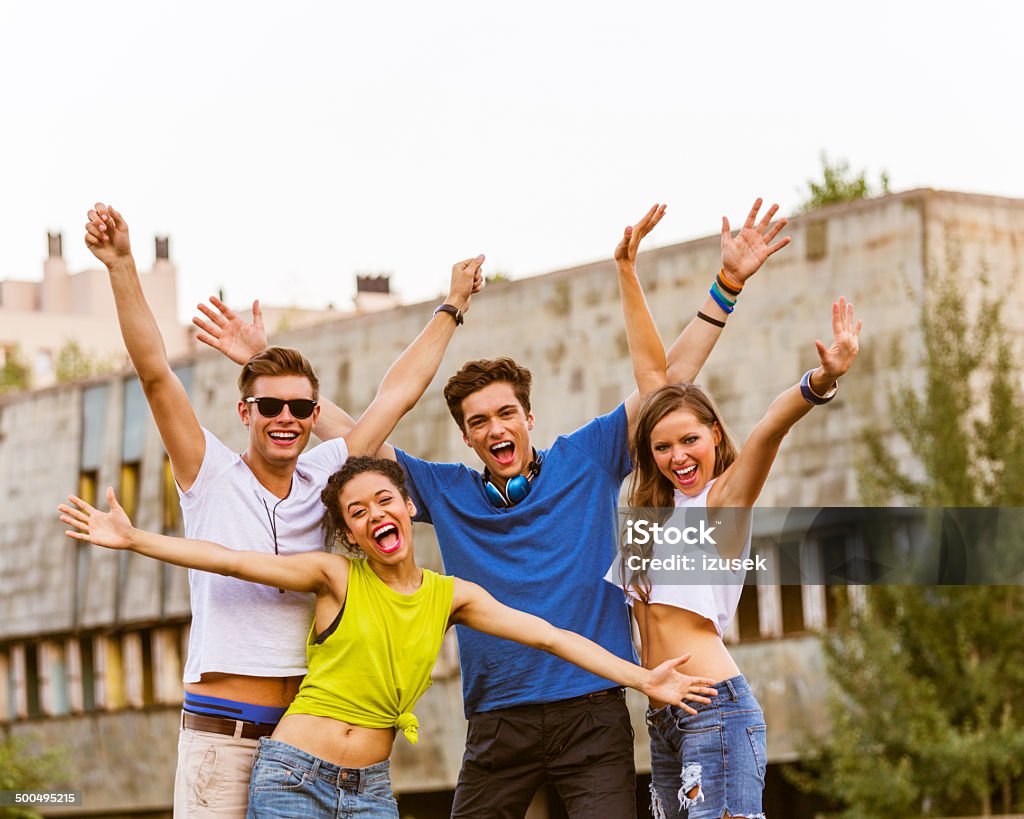 Happy urban young people Outdoor portrait of four happy friends laughing at camera with raised hands. Group Of People Stock Photo