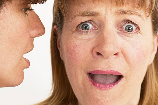 two women whisper a secret stock photo