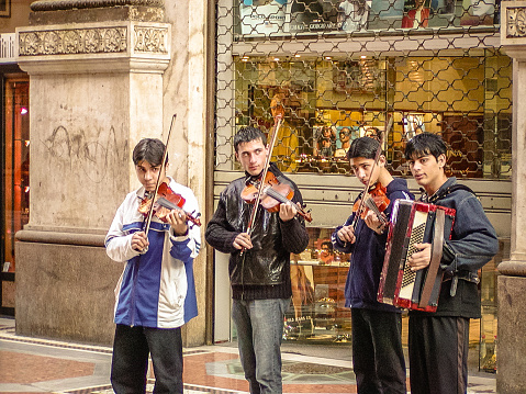 Milan, Italy - February 9, 2004: Group of teenagers playing music for tips in the Galleria Vittorio Emanuele II in central Milan.
