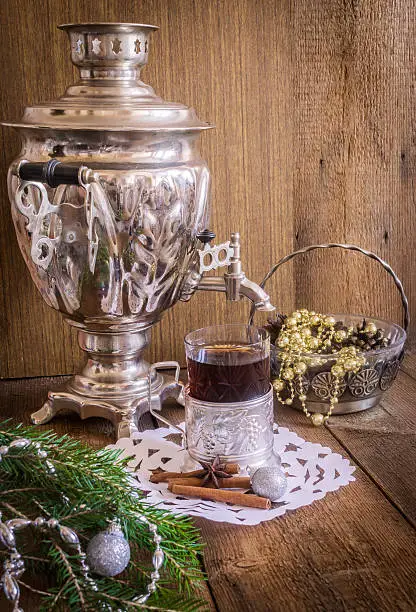 Tea in glass with coaster  and russian samovar on wooden background. Cinnamon and anise star with white doily. Home christmas decoration