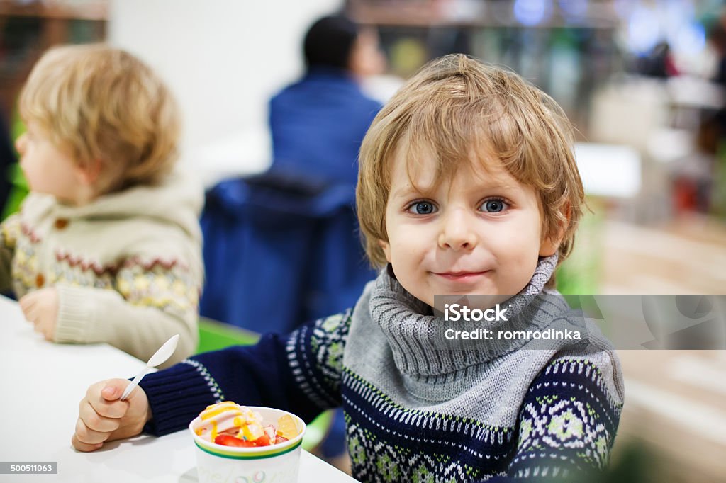 Little rubia niño pequeño niño comiendo un helado iin centro comercial - Foto de stock de 12-17 meses libre de derechos