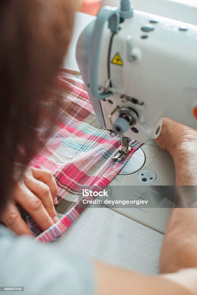 Women sew on sewing machine Women sew on sewing machine. White machine 2015 Stock Photo