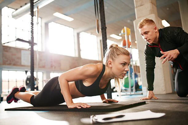 istock Female exercising with personal trainer at gym 500518472