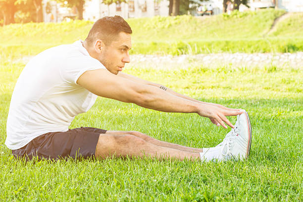 силуэт мужчины, физические упражнения сидя на траве вне в - sports training sit ups moving up sitting стоковые фото и изображения