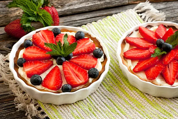 Sweet baskets with cream and strawberries and blueberry