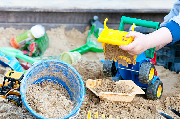 niño jugando en un cajón de arena en el patio de juegos - sandbox child human hand sand fotografías e imágenes de stock