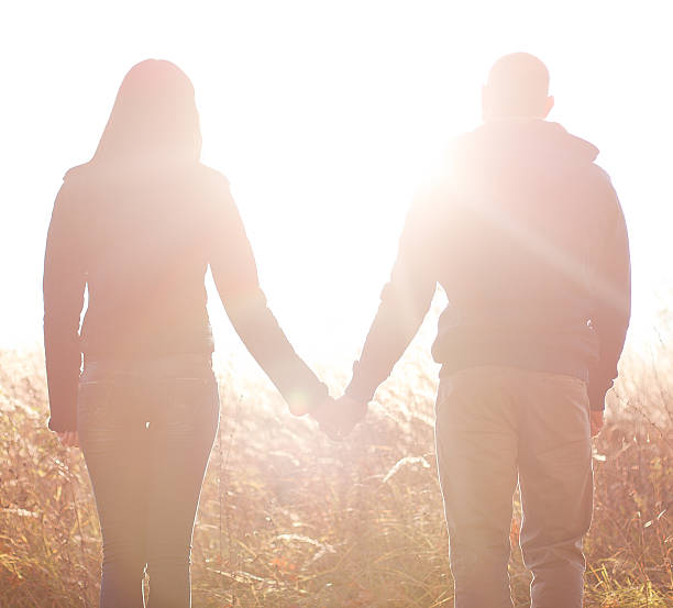 istock young couple holding hands. In Nature sunrise 500527329