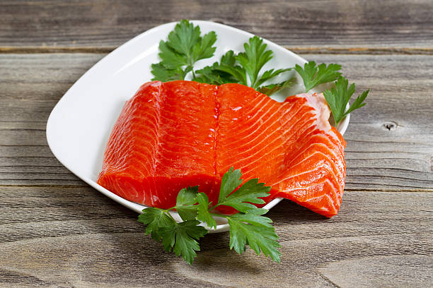 Fresh Salmon Fillet in white dish on rustic wood stock photo