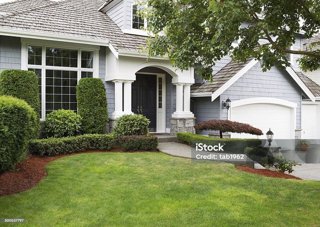 Newly painted and stained exterior of modern home during summert Newly painted exterior of a North American home during summertime with green grass and flower beds House Stock Photo