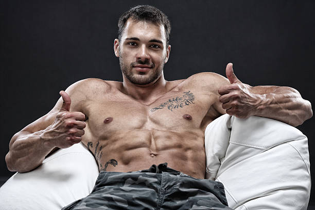 Chill out Muscular young man sitting in a leather chair-isolated on black background chest tattoos for men designs stock pictures, royalty-free photos & images