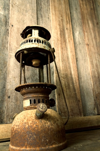 Old-fashioned lamp in an antique rustic country barn with aged wood wall and weathered wooden floor.