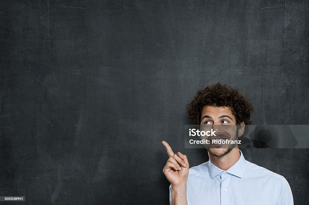 Happy Young Man Pointing Smiling Young Man Has An Idea Over Gray Background And Pointing At Your Text Or Product Chalkboard - Visual Aid Stock Photo