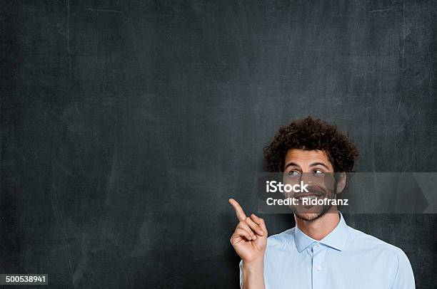 Happy Young Man Pointing Stock Photo - Download Image Now - Chalkboard - Visual Aid, Pointing, Men