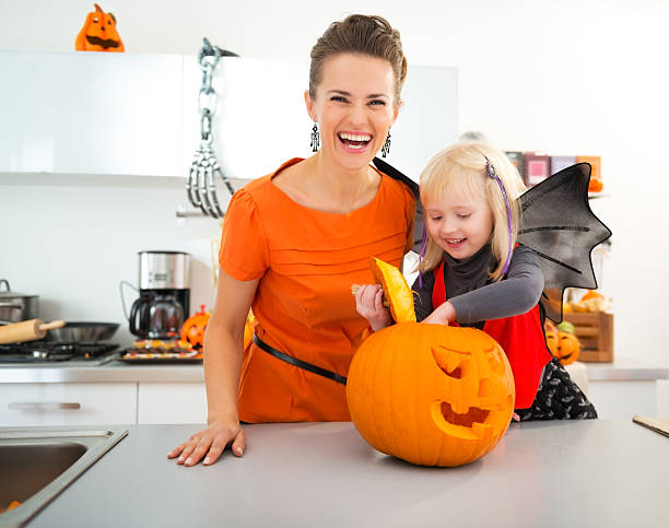 istock Halloween dressed girl with mother preparing Jack-O-Lantern 500540508