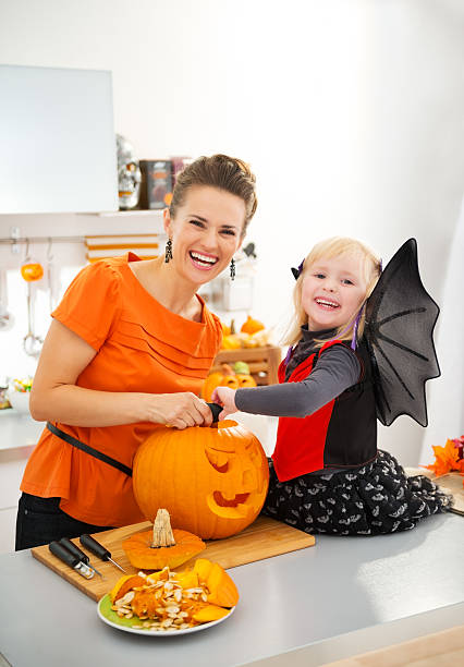 istock Mother with halloween dressed daughter carving Jack-O-Lantern 500540710