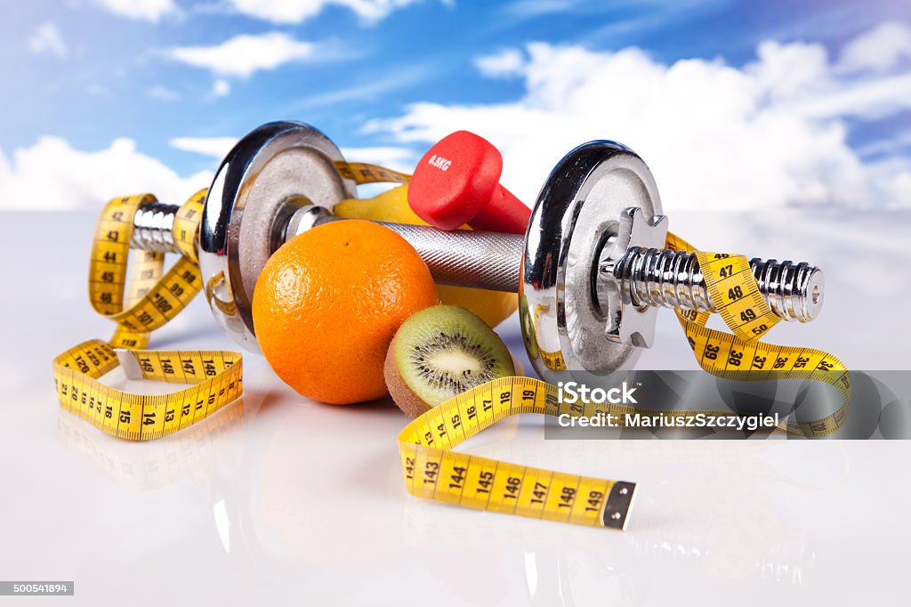 fitness dumbbell and healthy food metal dumbbells with fruits on blue sky background 2015 Stock Photo