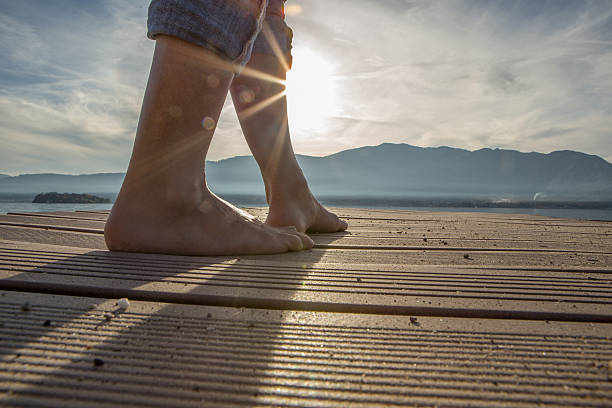 istock Woman walking barefoot on jetty above lake 500545686