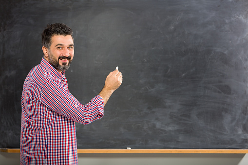 Young teacher writing on blackboard.