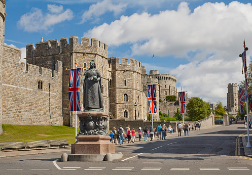 Windsor, United Kingdom - August 28, 2012: View of Windsor Castle, which is official residence of royal British family in Berkshire with Queen Victoria Statue on the foreground and the flow of tourists