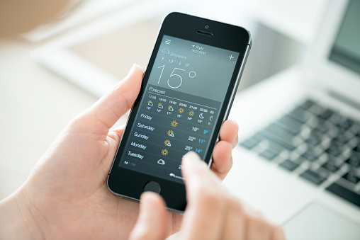 Kiev, Ukraine - June 27, 2014: Woman holding a brand new Apple iPhone 5S with application of weather forecast for the city of Kyiv. Developed by Apple inc. and was released on September 20, 2013.