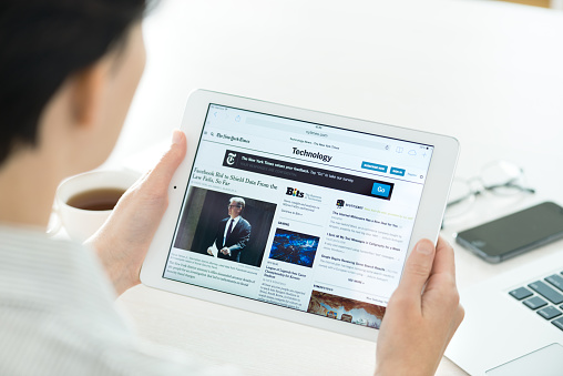 Kiev, Ukraine - June 27, 2014: Businesswoman reading The New York Times online article of technology news on a brand new Apple iPad Air. This website is one of America's most popular news site.