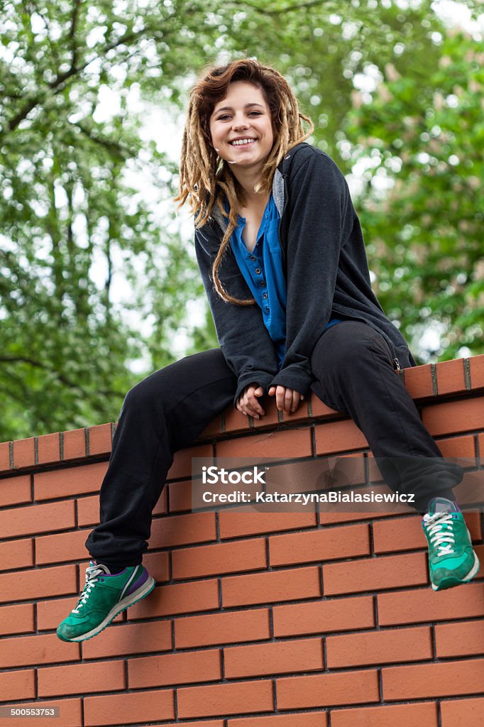 Original girl on the wall Original funny girl with dreads sitting on the wall Adult Stock Photo