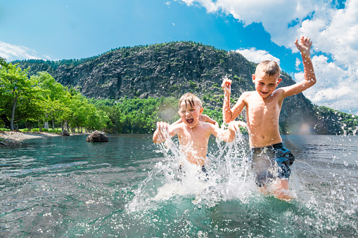 Boys having summer fun on Moosehead Lake in Maine by Mt Kineo in Kineo Bay. 