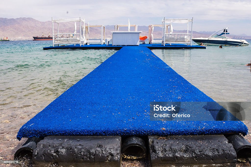 Bridge to Heaven A bridge to a wooden raft with 2 double beds and snack bar station . To the wooden raft connected a speed boat to go and have some fun in the sea. Blue Stock Photo