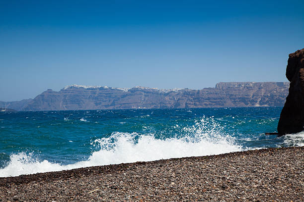 the famous Caldera in Santorini seen from a beach with volcanic pebbles